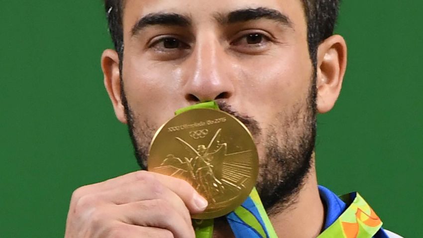 Iran's gold medallist Kianoush Rostami poses on the podium after the men's weightlifting 85kg event during the Rio 2016 Olympics Games in Rio de Janeiro on August 12, 2016. / AFP / GOH Chai Hin        (Photo credit should read GOH CHAI HIN/AFP/Getty Images)