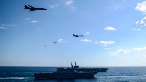 B-1B  bombers and F/A-18 strike fighters fly over a Japanese carrier and the USS Theodore Roosevelt.