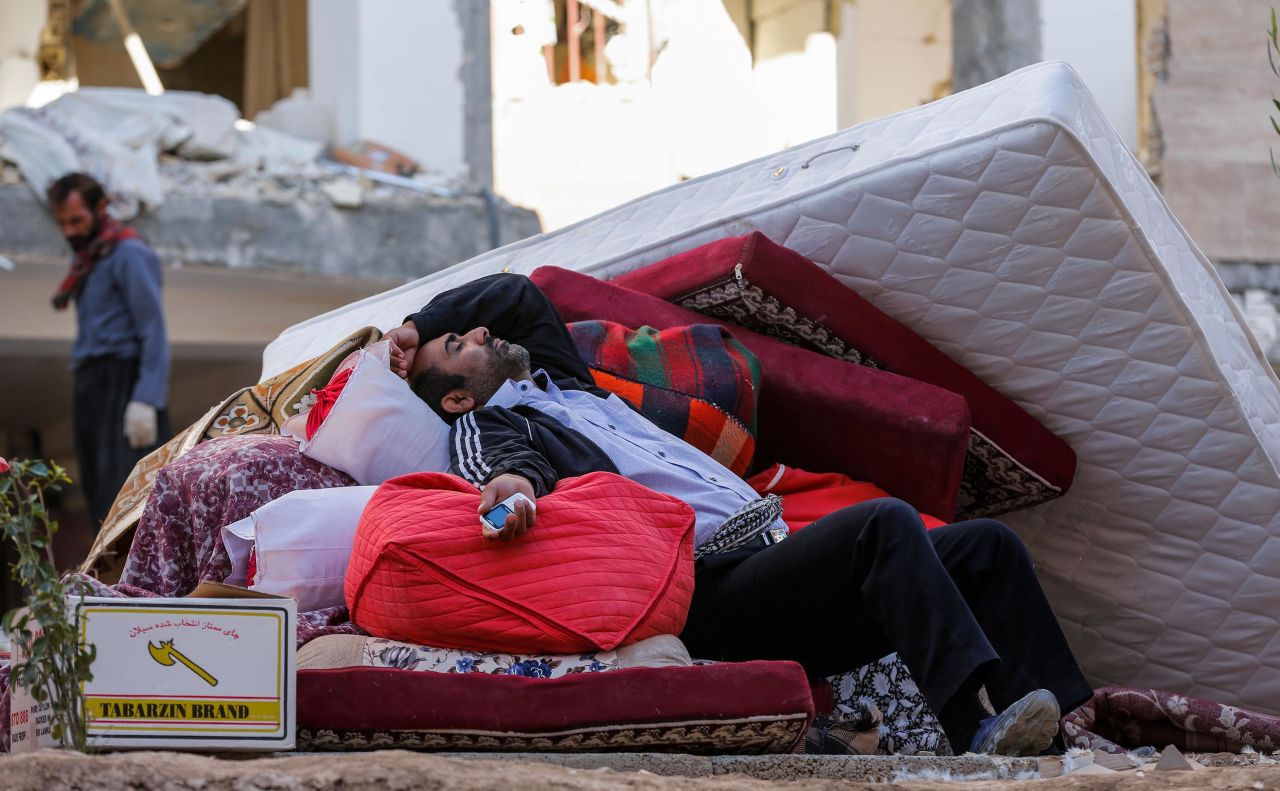 A man rests atop salvaged belongings in Sarpol-e Zahab.