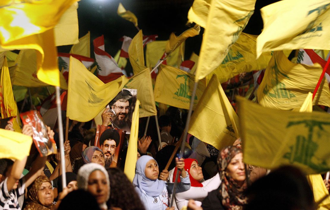 Images of Hezbollah chief Hassan Nasrallah are seen among scores of Hezbollah and Lebanese national flags being waved by Hezbollah supporters.
