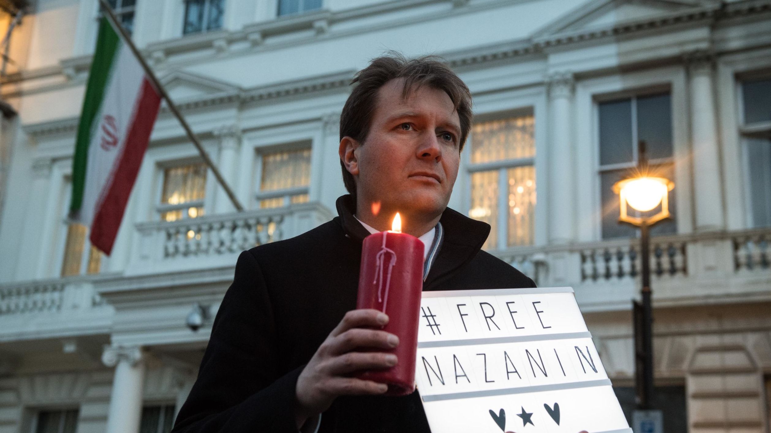 Richard Ratcliffe holds a "#Free Nazanin" sign and candle during a vigil for his wife outside the Iranian Embassy in London in January 2017. 