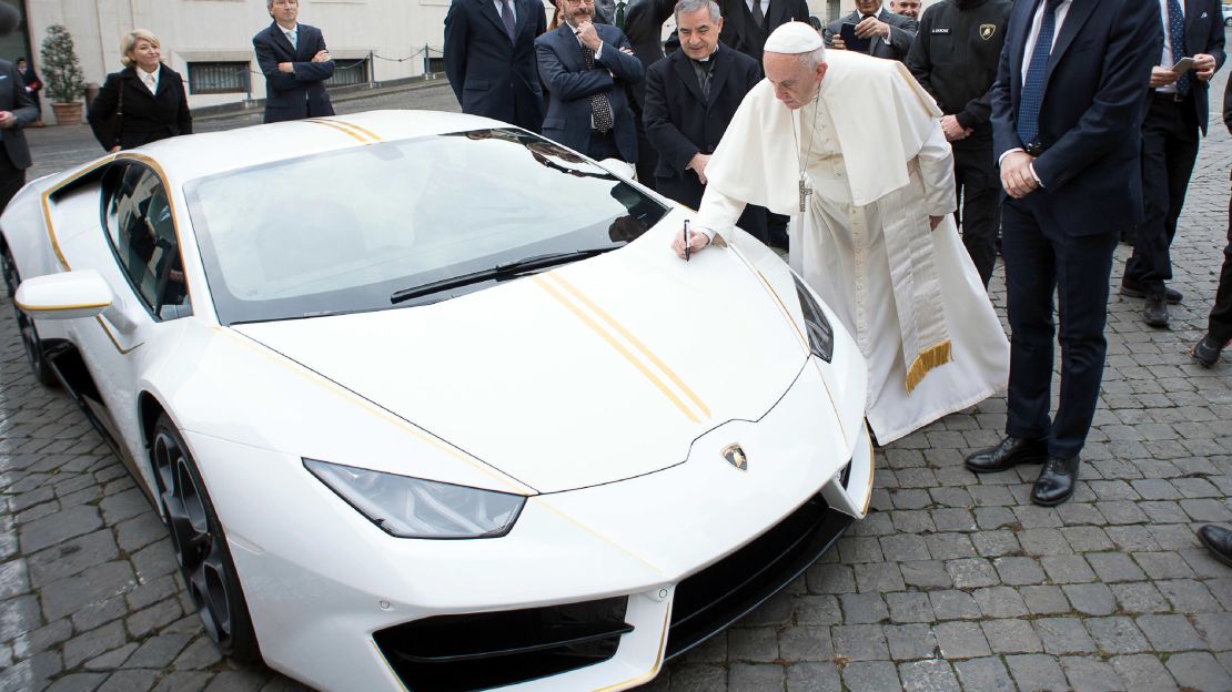 Pope Francis writes on the hood of a Lamborghini donated to him by the luxury sports car maker on Wednesday, November 15. 