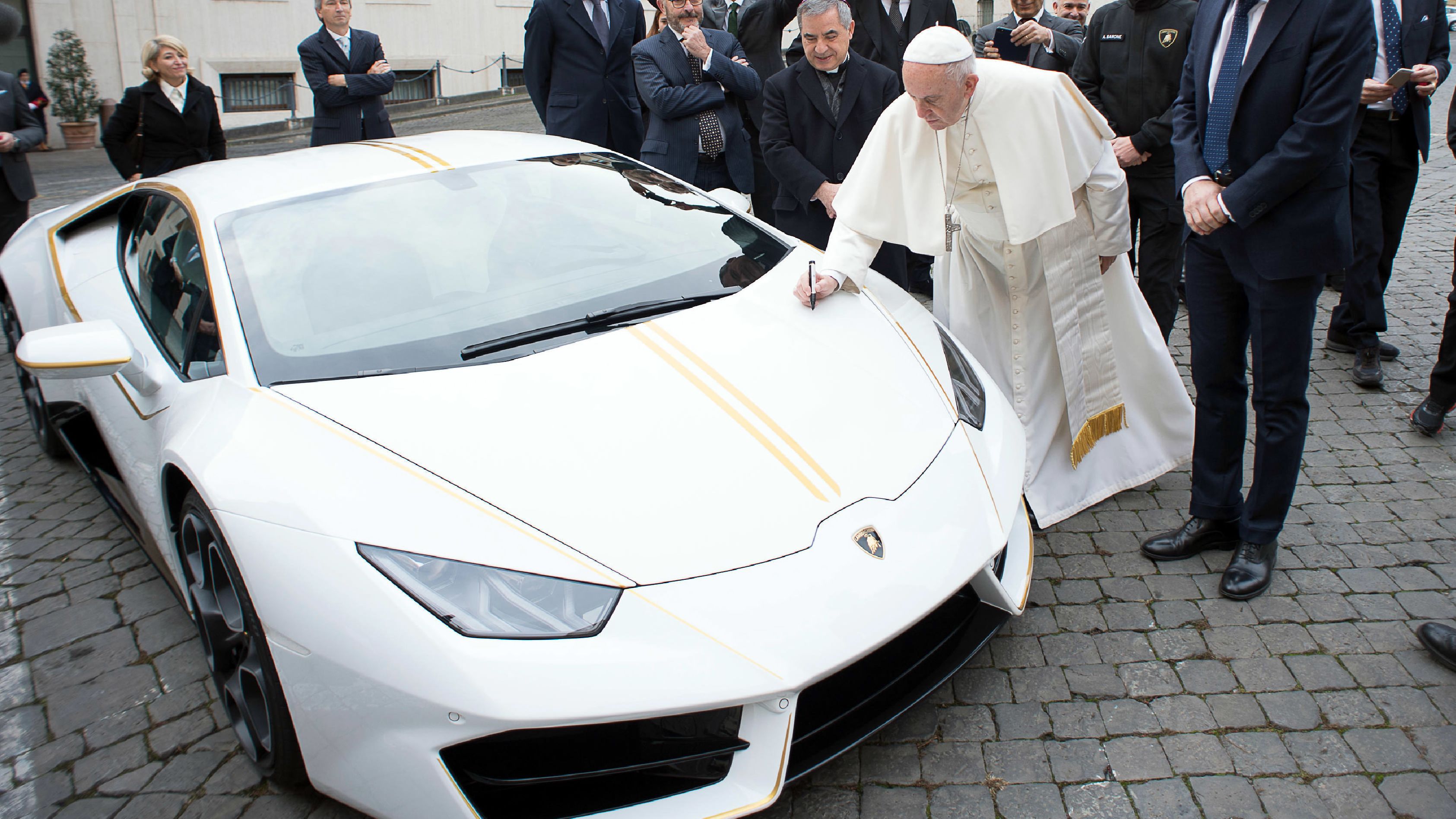 Pope Francis writes on the hood of a Lamborghini donated to him by the luxury sports car maker, at the Vatican.