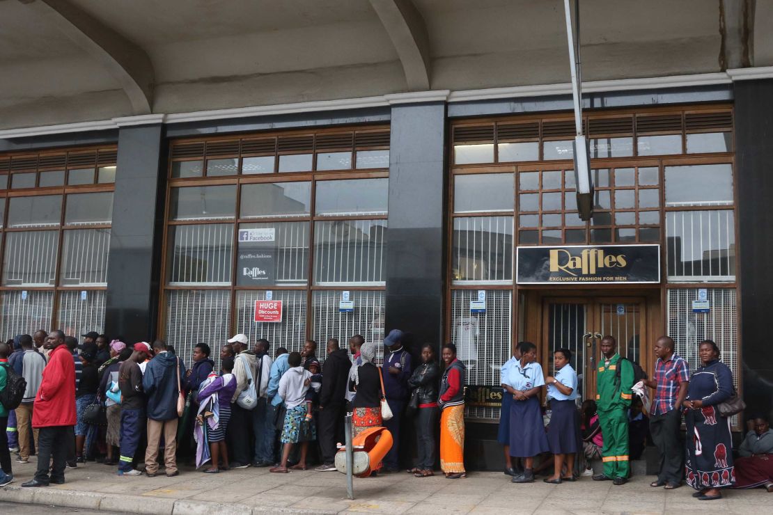 People wait Wednesday to withdraw cash outside a bank in Harare.
