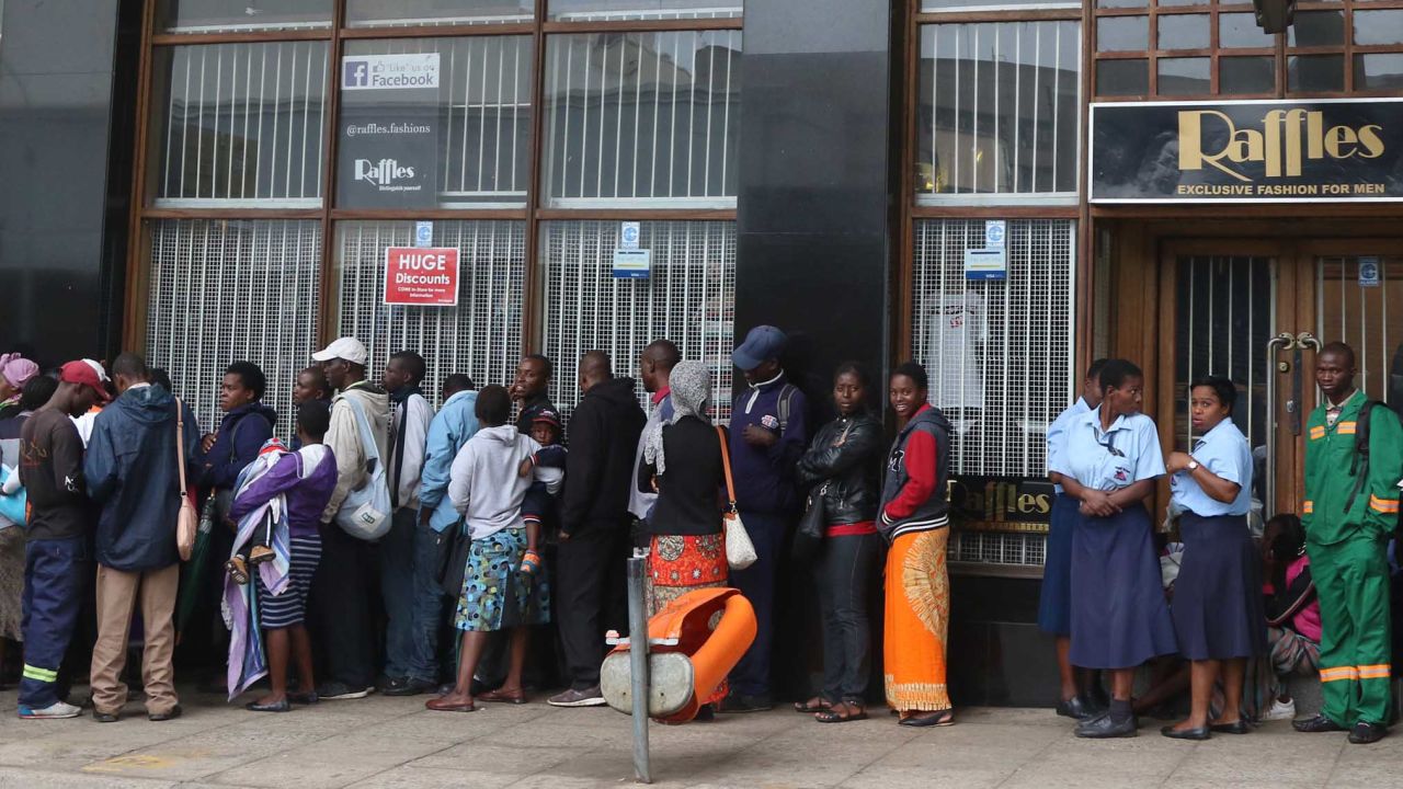 People wait Wednesday to withdraw cash outside a bank in Harare.