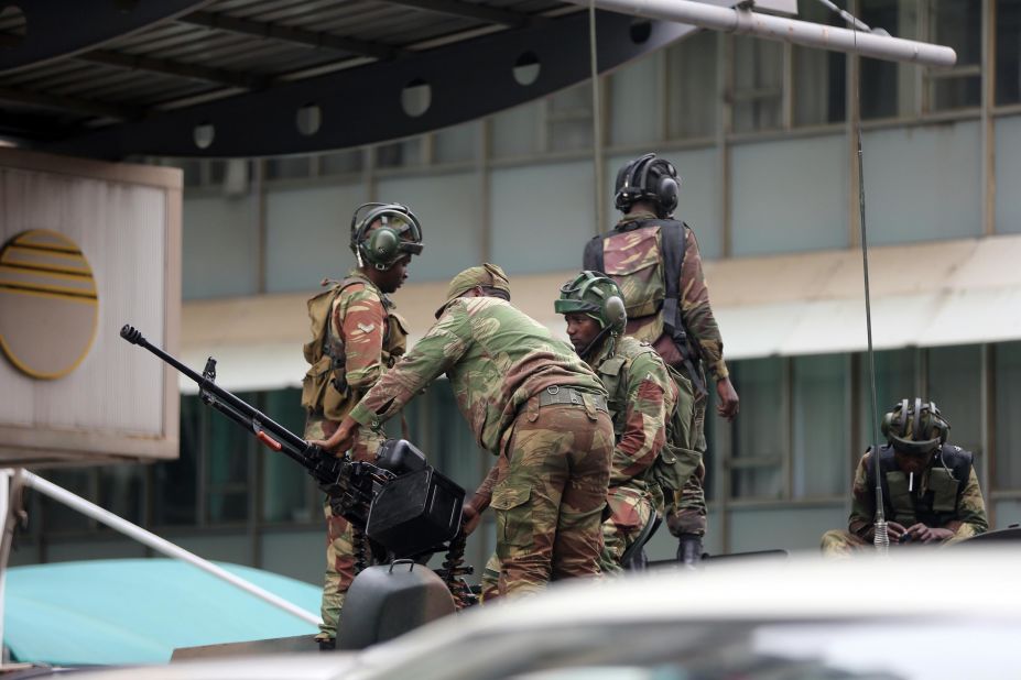 Members of the military check a gun as they stand atop an armored vehicle parked in Harare's central district on November 16.