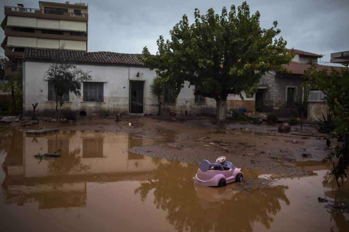 A toy car drifts on a flooded street next to a damaged house in Mandra on Wednesday.
