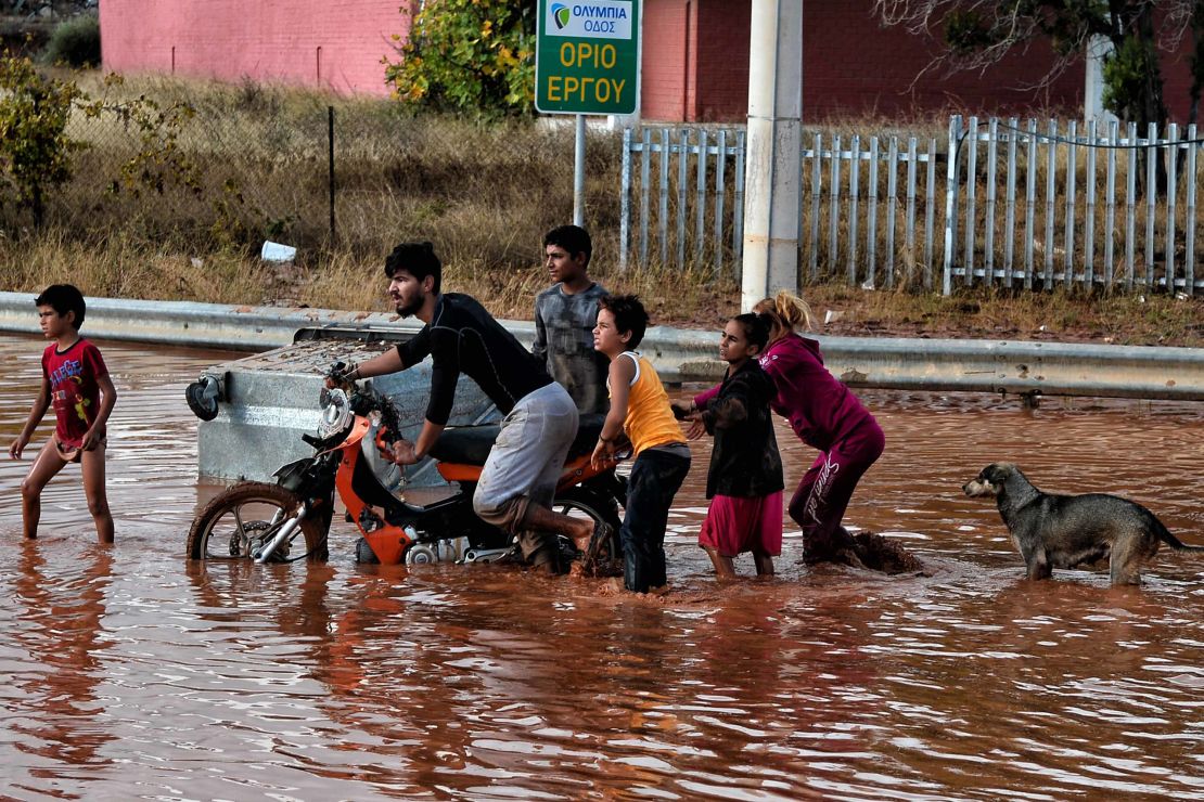 Youths make their way on a flooded street Wednesday in Mandra.
