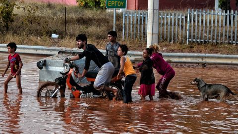 Youths make their way on a flooded street Wednesday in Mandra.
