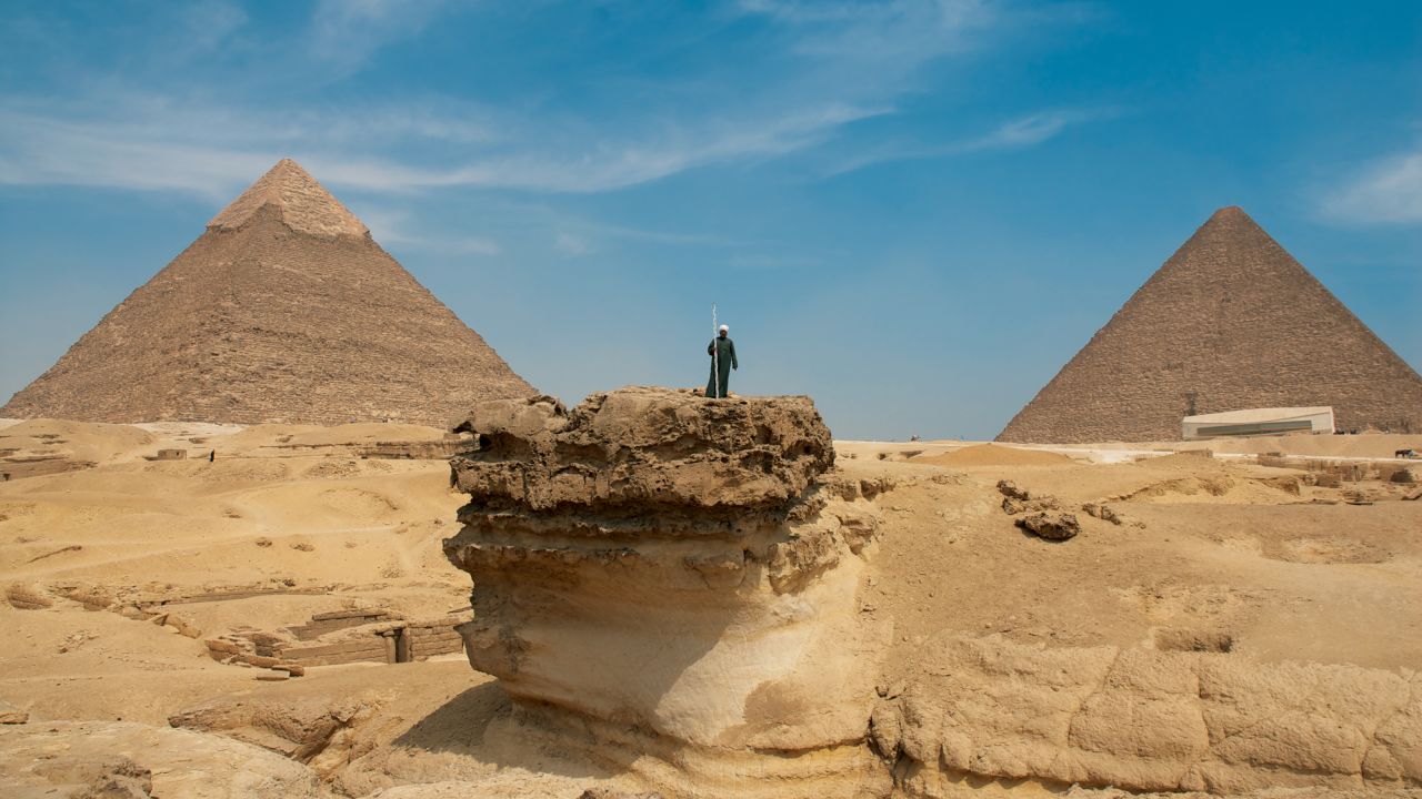A man stands on an outcrop on the Giza plateau, surrounded by land quarried in antiquity.