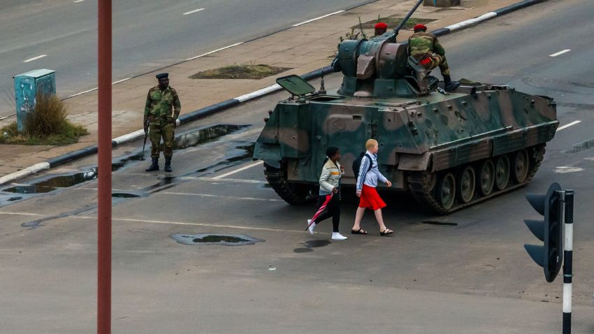 TOPSHOT - Young women walk past an armoured personnel carrier that stations by an intersection as Zimbabwean soldiers regulate traffic in Harare on November 15, 2017.
Zimbabwe's military appeared to be in control of the country on November 15 as generals denied staging a coup but used state television to vow to target "criminals" close to President Mugabe. / AFP PHOTO / -        (Photo credit should read -/AFP/Getty Images)