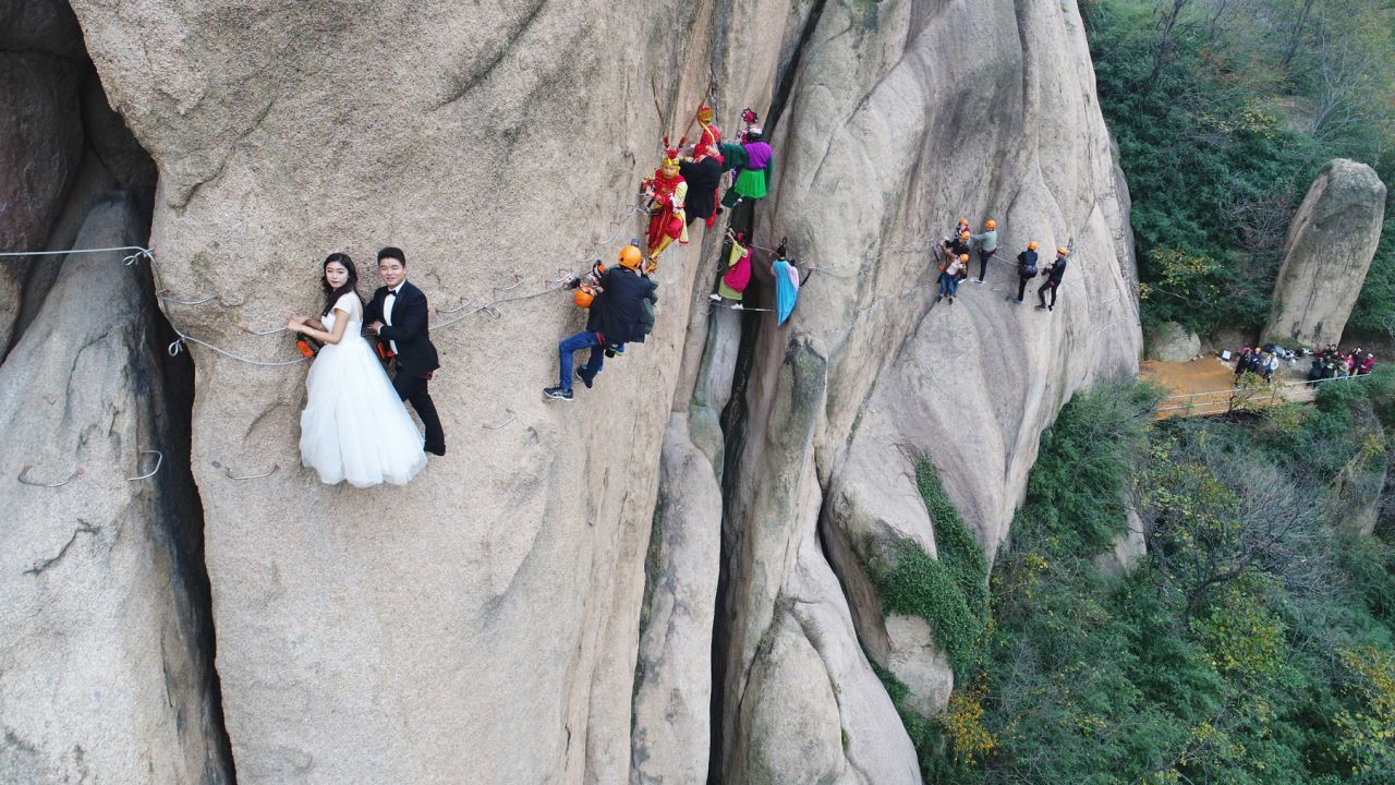 A couple takes a wedding photo while hanging off a cliff in Zhumadian, China, on Saturday, November 11.