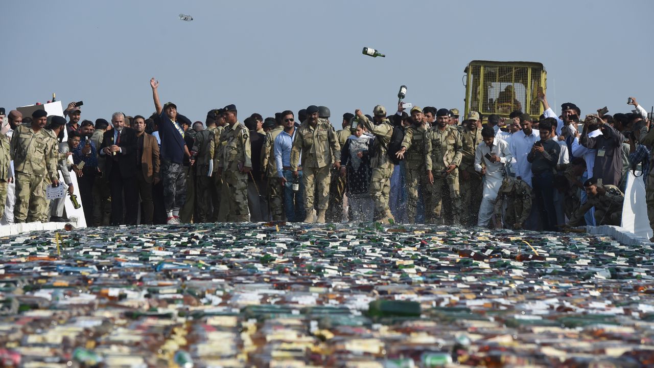 Officials with the Pakistan Coast Guards throw confiscated bottles of liquor before destroying them on the outskirts of Karachi on Monday, November 13.
