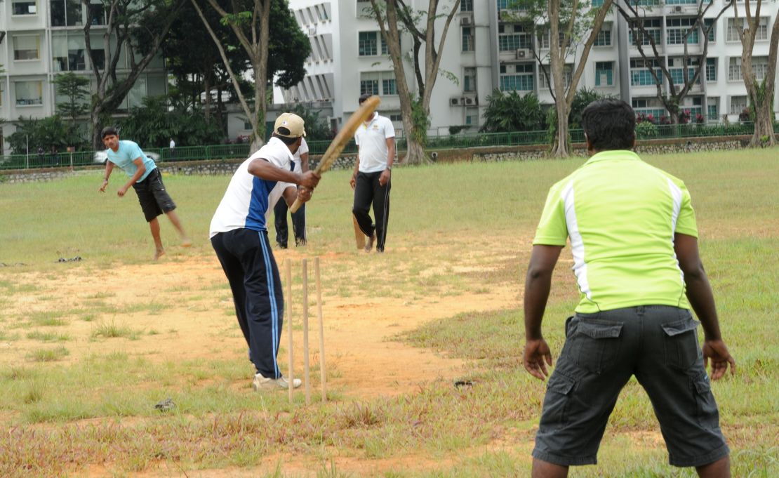 South Asian workers play a cricket game on the field next to Little India district in Singapore on December 15, 2013. 