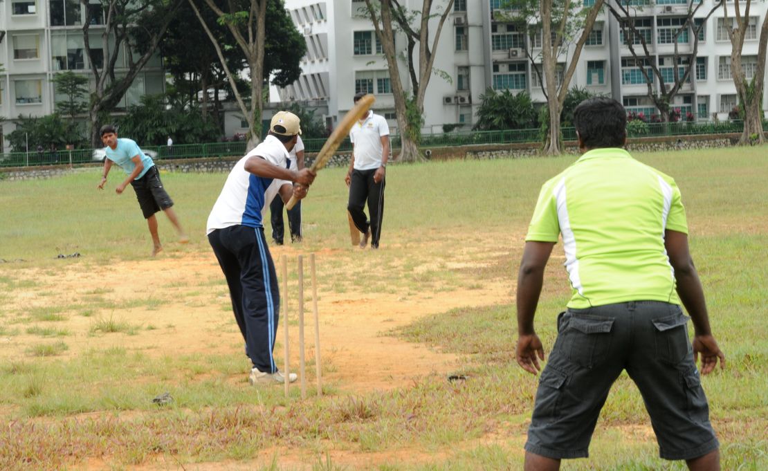 South Asian workers play a cricket game on the field next to Little India district in Singapore on December 15, 2013.
