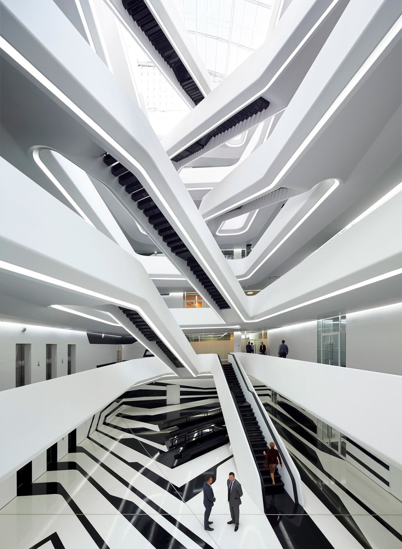 A central atrium rises through the center of the building, with interconnected staircases joining the indoor balconies. Natural light floods in from the glass roof.