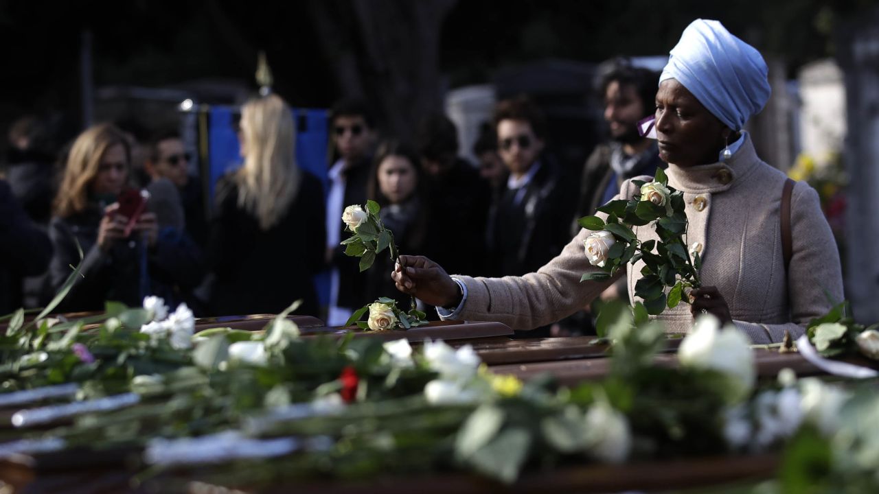 A woman places flowers on coffins during the service in Salerno. 