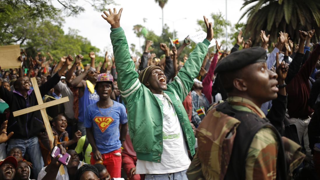 People in Harare react as they see a military helicopter fly overhead during protests against Mugabe on November 18.