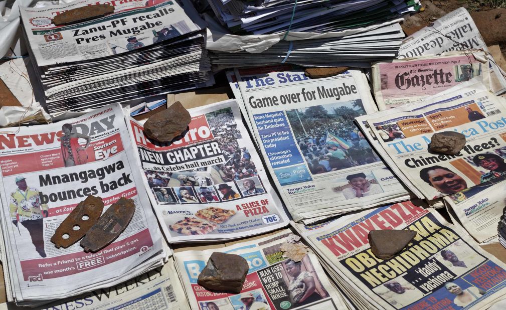 Newspapers are held in place with rocks at a newsstand in Harare on November 20.