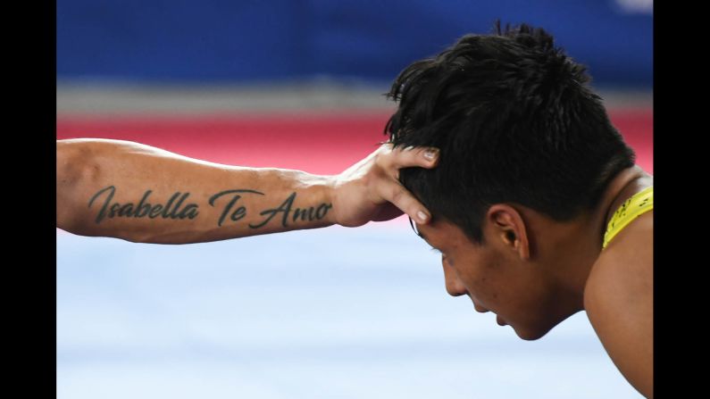 Peruvian wrestler Sixto Auccapina, right, is held at arm's length by Colombia's Hernan Guzman during the Bolivarian Games on Tuesday, November 14. Guzman's tattoo reads "Isabella Te Amo" ("I love you Isabella").