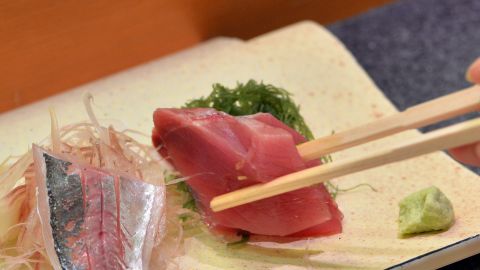 This photo taken on July 16, 2013 shows a customer eating bonito and horse mackerel sashimi (raw fish) at a high-end sushi restaurant in Tokyo.  There is no menu and the chef selects the best fish available for customers, which costs at least 10,000 yen (100 USD) per person. While high-end restaurants cater to regular client?le, many traditional sushi restaurants - a business steeped in tradition - nowadays must compete with "kaiten" or revolving sushi restaurants where raw fish slices atop rice balls travel on conveyor belts along counters waiting to be picked up by diners, with some offering dishes for as cheap as 100 yen (1 USD).  A key challenge to both high-end eateries and fast food sushi kitches is that Japanese people are eating less fish and more meat these days as world prices rise due to strong demand in the United States and Europe.      AFP PHOTO / Yoshikazu TSUNO        (Photo credit should read YOSHIKAZU TSUNO/AFP/Getty Images)