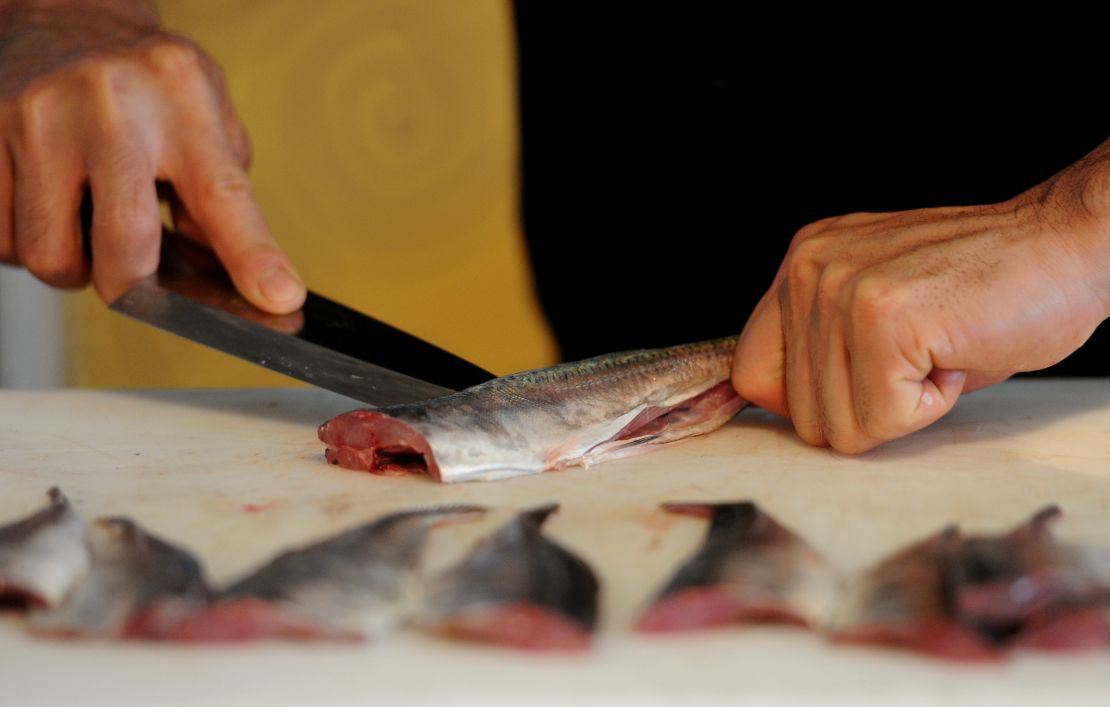 A Japanese chef slices sea bream during a sushi demonstration.