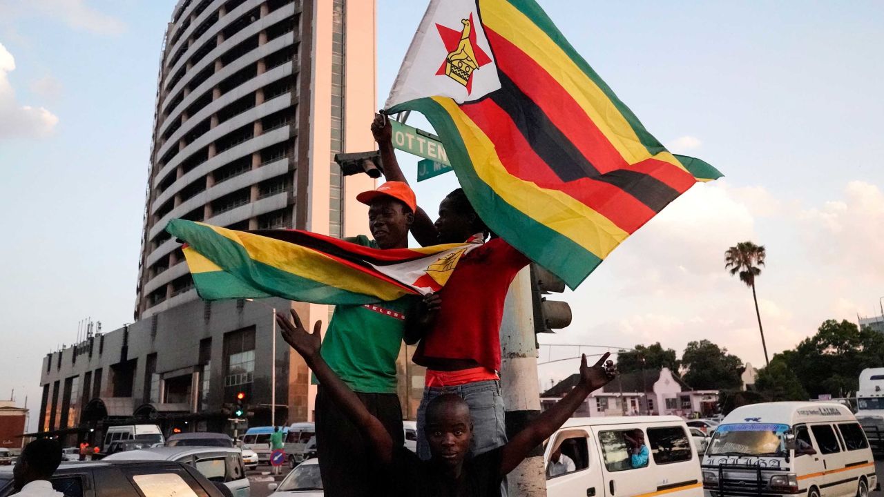 People holding Zimbabwean flags celebrate in the street after the resignation of Zimbabwe's president on November 21, 2017 in Harare.
Car horns blared and cheering crowds raced through the streets of the Zimbabwean capital Harare as news spread that President Robert Mugabe, 93, had resigned after 37 years in power. / AFP PHOTO / Marco Longari        (Photo credit should read MARCO LONGARI/AFP/Getty Images)