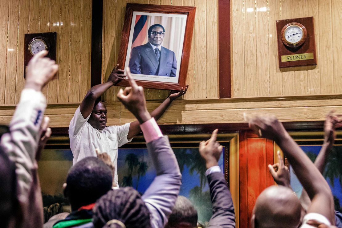 People remove a portrait of former President Mugabe.
