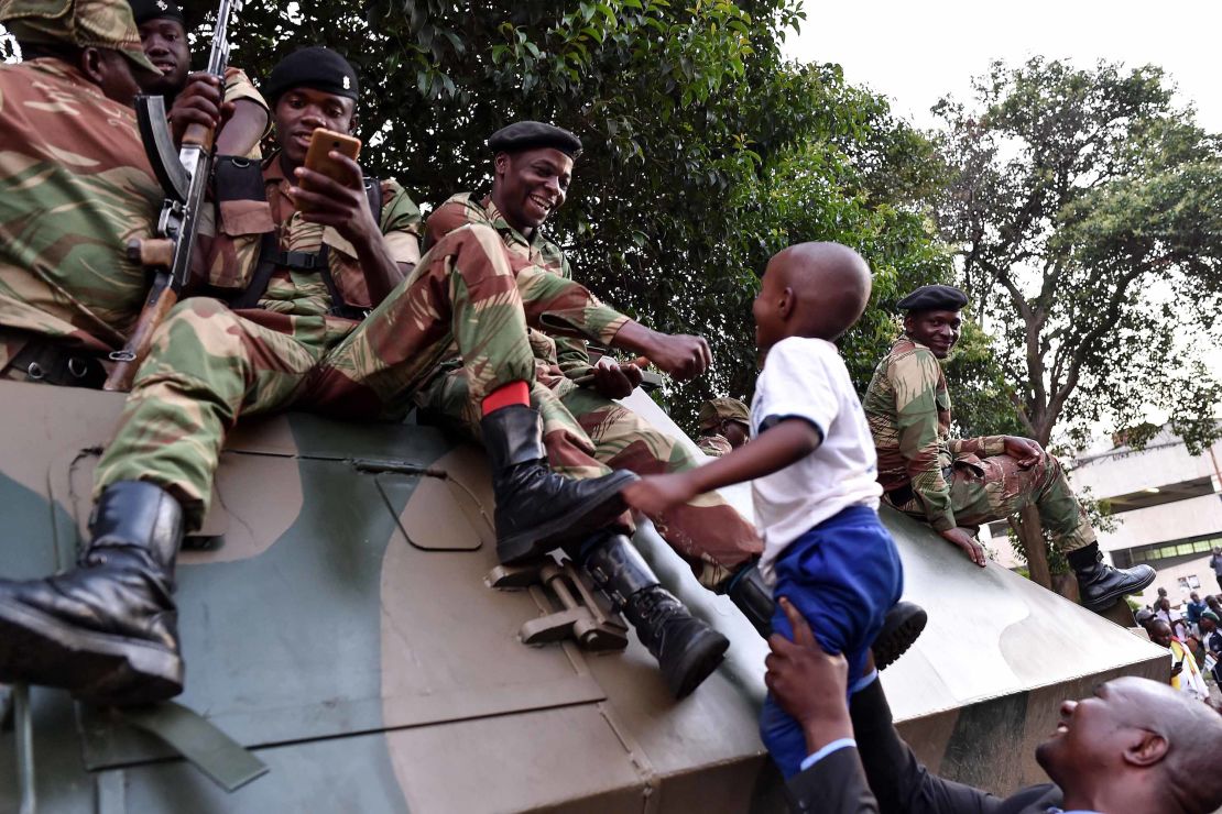Zimbabweans celebrate outside Parliament; soldiers hoist a child up onto their tank following the announcement. 