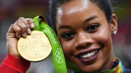 RIO DE JANEIRO, BRAZIL - AUGUST 09:  Gabrielle Douglas of the United States poses for photographs with her gold medal after the medal ceremony for the Artistic Gymnastics Women's Team on Day 4 of the Rio 2016 Olympic Games at the Rio Olympic Arena on August 9, 2016 in Rio de Janeiro, Brazil.  (Photo by Laurence Griffiths/Getty Images)