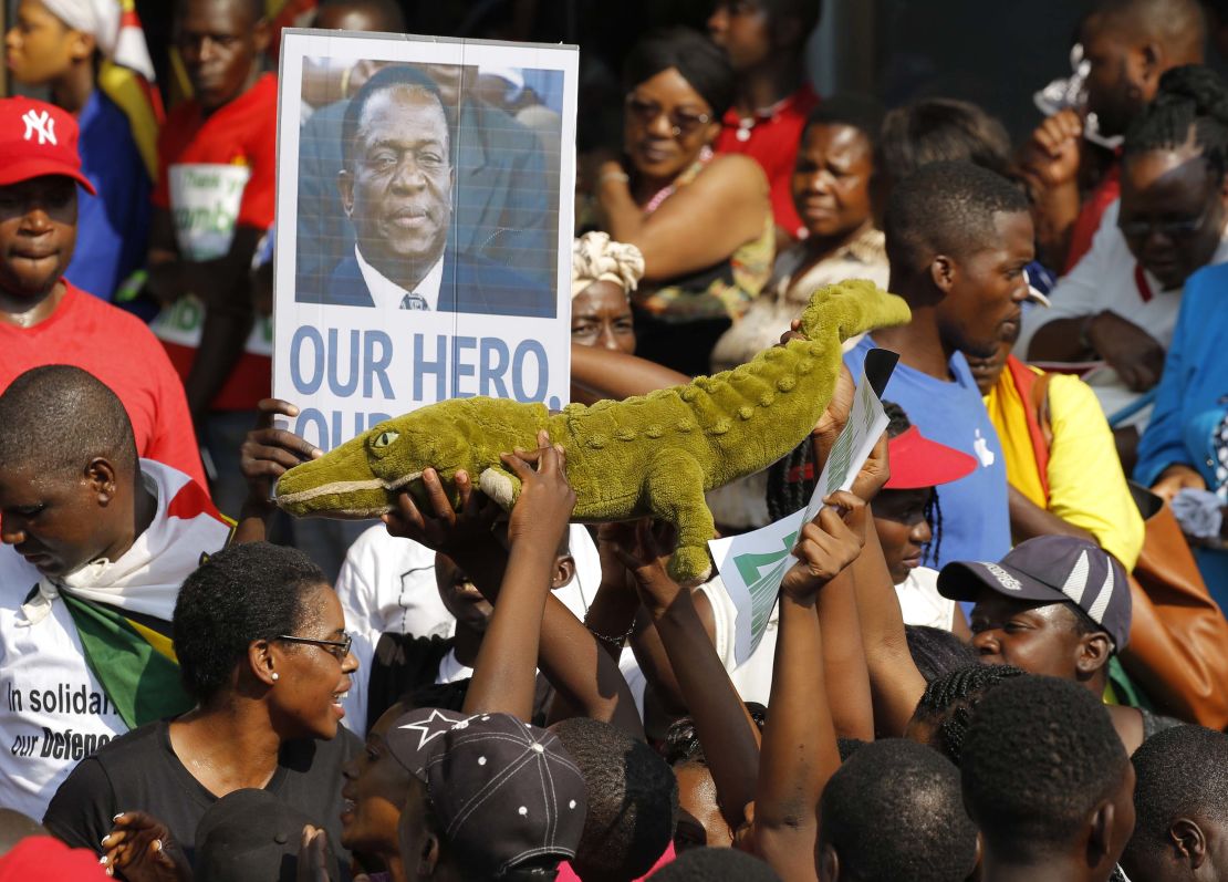 Supporters of Emmerson Mnangagwa hold up a toy to celebrate the man nicknamed 'The Crocodile' as they waited at an airport for his arrival Wednesday. 