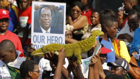 Supporters of Emmerson Mnangagwa hold up a toy to celebrate the man nicknamed 'The Crocodile' as they waited at an airport for his arrival Wednesday.