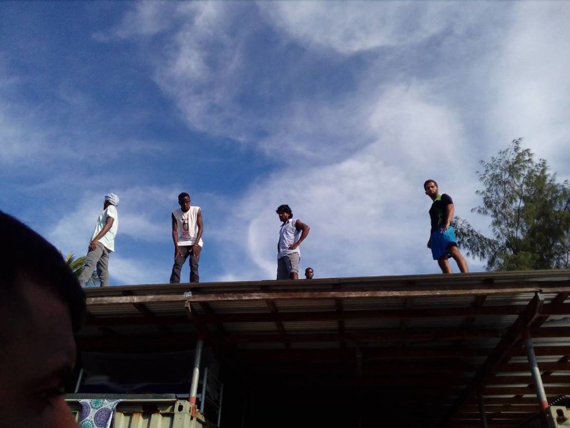 Residents of the Manus island refugee camp stand on the roof of a structure in the now-shuttered facility on Thursday, November 23.