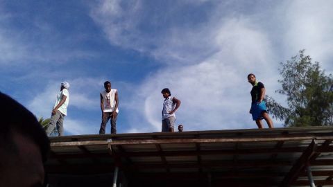 Residents of the Manus island refugee camp stand on the roof of a structure in the now-shuttered facility on Thursday, November 23.