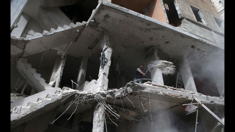 A man shovels away debris from a building that was shelled in the rebel-held town of Kafr Batna, Syria, on Monday, November 20.