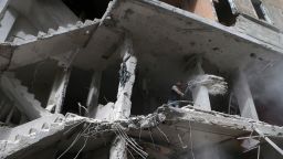 A Syrian shovels away debris from the higher floor of a building that was reportedly shelled by regime forces in rebel-held Eastern Ghouta.