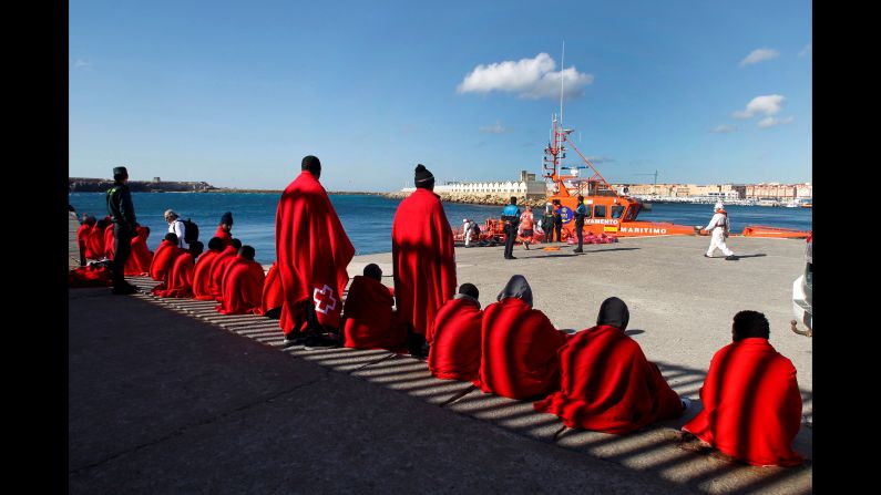Migrants cover themselves with Red Cross blankets as they wait to be transferred at the port of Tarifa, Spain, on Saturday, November 18. The migrants were rescued while crossing the Strait of Gibraltar on two small boats.