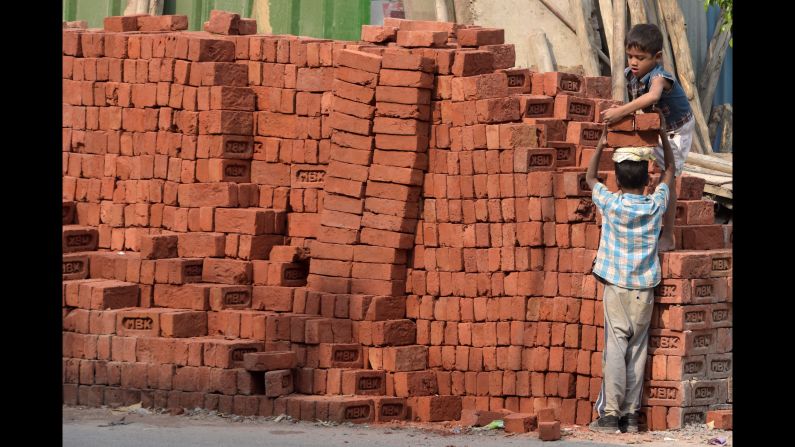 Children load bricks at a building site in New Delhi on Sunday, November 19.