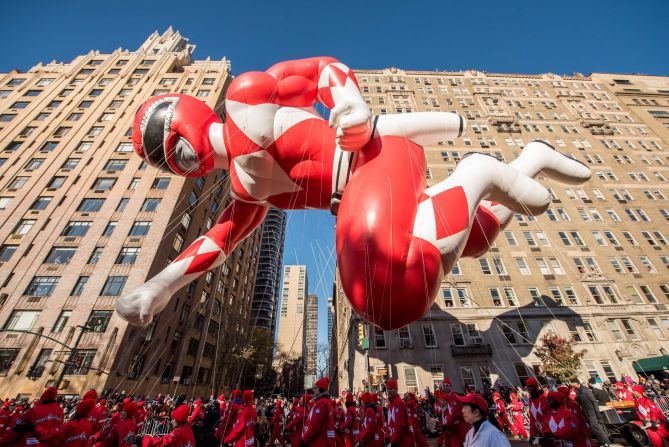 A Power Ranger balloon is held by handlers.