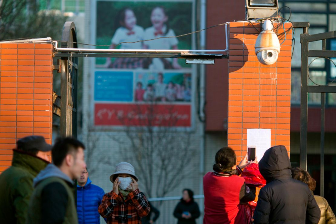 People take photos of a notice posted by the RYB kindergarten announcing measures taken in response to allegations of children abuse in Beijing, Friday.