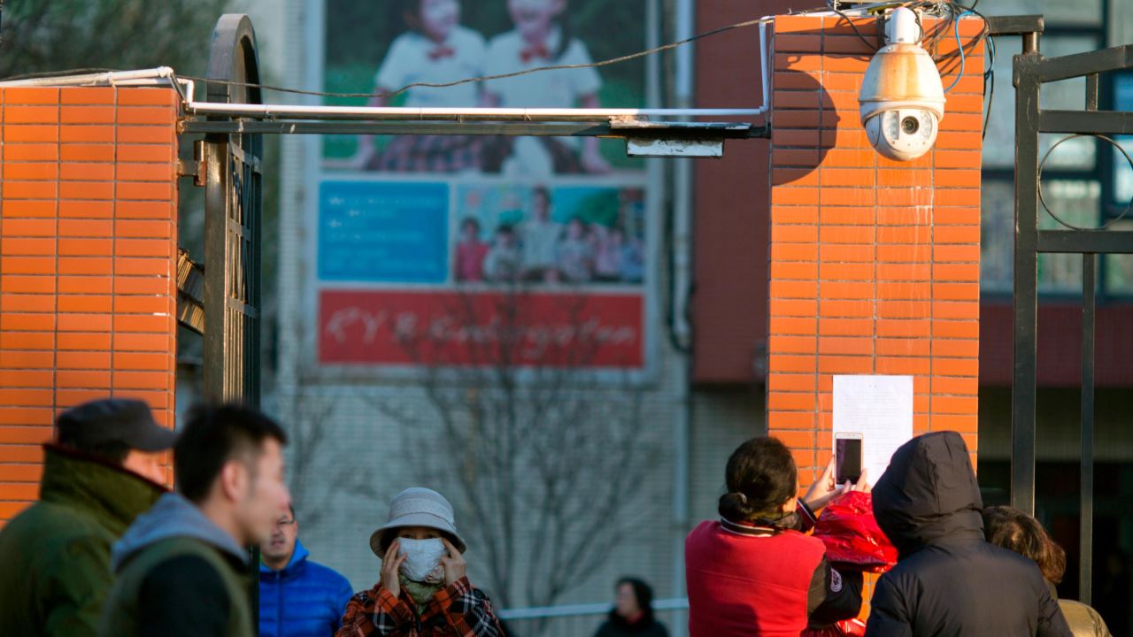 Parents take photos of a notice posted by the RYB kindergarten announcing measures taken in response to allegations of children abuse in Beijing, China.