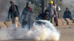 A Pakistani protester of the Tehreek-i-Labaik Yah Rasool Allah Pakistan (TLYRAP) religious group throws a tear gas shell back towards police during a clash in Islamabad on November 25, 2017.