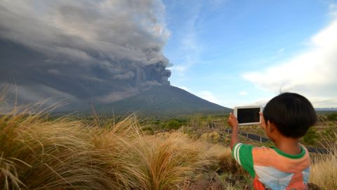 A boy takes pictures during Mount Agung's eruption on Indonesia's resort island of Bali on November 26,
