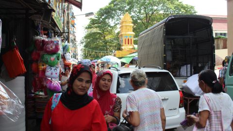 Two women wearing veils walk along a street in central Yangon with a Hindu temple in the background on September 21, 2017. 