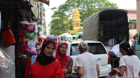 Two women wearing veils walk along a street in central Yangon with a Hindu temple in the background on September 21, 2017.