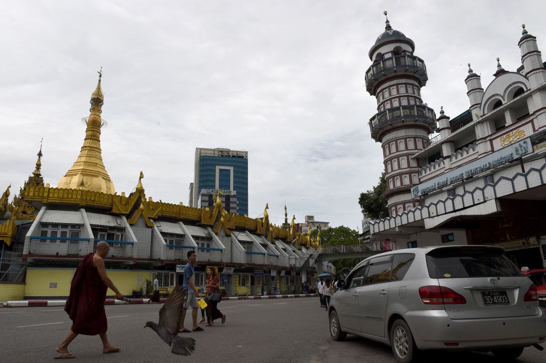 A Buddhist monk  crosses a street intersection fronting Sule pagoda, left, and the Bengali Sunni Jameh mosque right, in Yangon. 