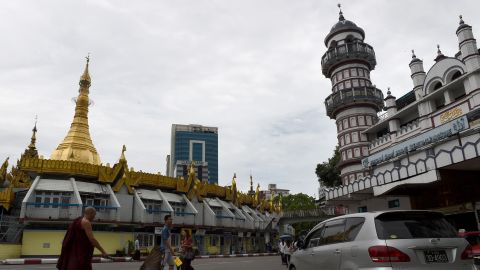 A Buddhist monk  crosses a street intersection fronting Sule pagoda, left, and the Bengali Sunni Jameh mosque right, in Yangon. 