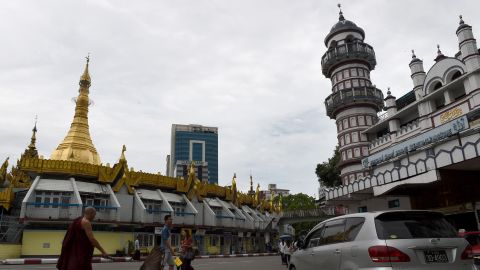 A Buddhist monk crosses a street intersection fronting Sule pagoda, left, and the Bengali Sunni Jameh mosque right, in Yangon.