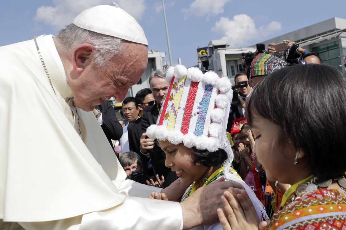 Pope Francis is greeted by young children in traditional clothes upon his arrival at Yangon's airport in Myanmar.
