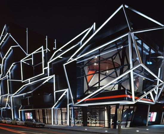 Facade lighting is used to illuminate the Melbourne Theatre Company building's white pipework, creating the appearance of a two-dimensional drawing.